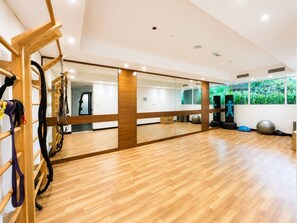 A gym with wooden flooring, exercise equipment, and a large mirror. - FIRST CLASS | 1BR | Effortless Elegance (JVC)