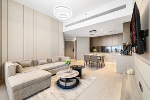 Ein modernes Wohnzimmer mit einer Eckcouch, einem runden Couchtisch und einem Essbereich mit Tisch und Stühlen.