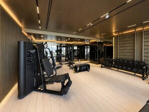 A modern gym with various exercise equipment, including a weight bench and a squat rack. - FIRST CLASS | 1BR | Close to Downtown Attractions (Dubai)