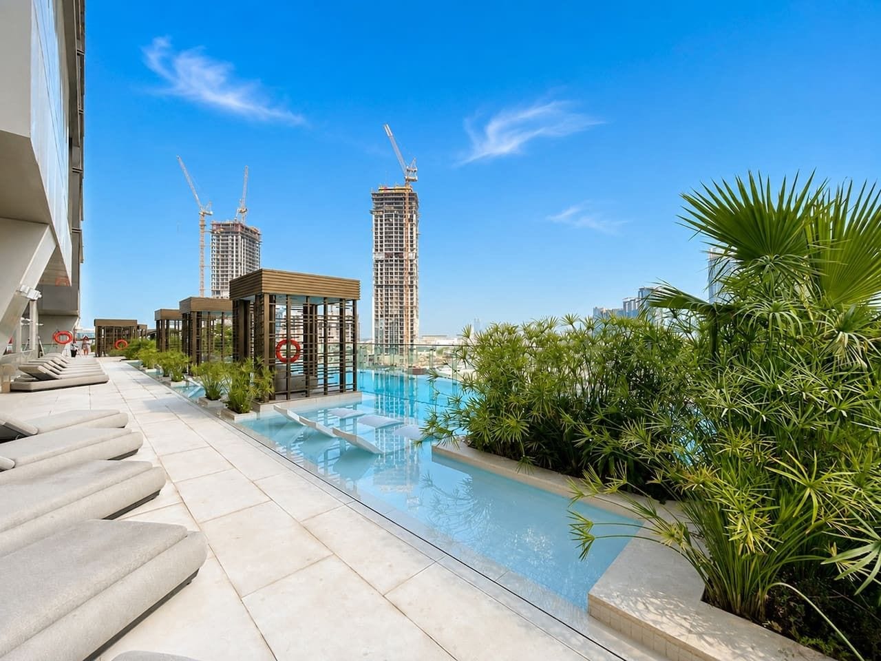 Un área de piscina en la azotea con vistas despejadas al perfil urbano, incluyendo grúas de construcción.