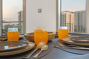 A table set for two with plates, cutlery, and glasses of orange beverage. - FIRST CLASS | 1BR | Cozy Escape | Near Downtown (Meydan)