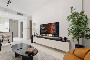 Una sala moderna con televisor grande, zona de comedor y planta en maceta.