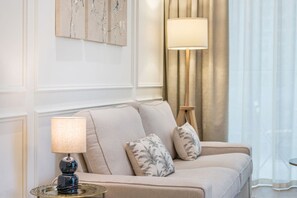 A room with a sofa, a lamp, and a painting on the wall. - FIRST CLASS | 1BR | Chic Retreat | Luxury Escape (JVC)