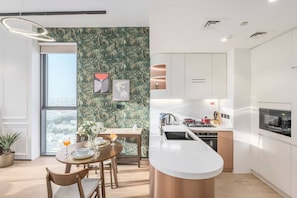 A modern kitchen with white cabinets, a stainless steel sink, and a copper island. - FIRST CLASS | 1BR | Chic Retreat | Luxury Escape (JVC)
