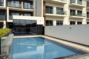 Ein modernes Gebäude mit Schwimmbad, Glasgeländern und einer flachen Dachkonstruktion.
