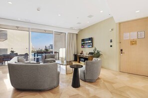 A modern hotel lobby with a large window offering a city view, a flat-screen TV mounted on the wall, and a reception desk. - FIRST CLASS | 3BR | FIVE Palm | Beachfront Luxury (Palm Jumeirah)