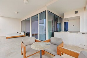 A modern living room with a sofa, a round table, and a view through large glass doors. - FIRST CLASS | 3BR | FIVE Palm | Beachfront Luxury (Palm Jumeirah)