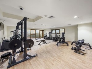 Ett gym med olika typer av träningsutrustning, inklusive styrketräningsmaskiner, lösa vikter och konditionsmaskiner.