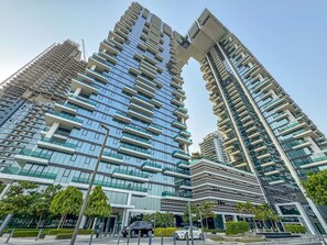 Een hoog gebouw met meerdere balkons, een modern architectonisch ontwerp en een heldere lucht.