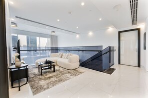 Ein modernes Wohnzimmer mit einer Eckcouch, einem Couchtisch und einer Treppe mit Glastrennwand.