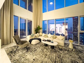 A modern living room with a sectional sofa, a chair, a coffee table, and large windows offering a city view. - FIRST CLASS |Penthouse| Elevated Luxe| Attractions (Al Wasl)