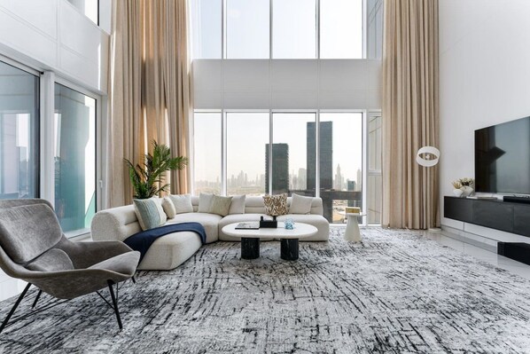Een moderne woonkamer met een modulaire bank, een ronde salontafel en een televisie.
