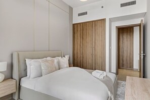 A hotel room with a bed, bedside table, and a wardrobe. - FIRST CLASS | 1BR | Luxury Escape | Near Downtown (Meydan)