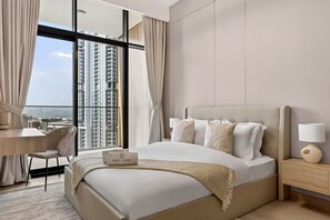A modern hotel room with a large bed, a desk, and a view of high-rise buildings. - FIRST CLASS | 1BR | Luxury Escape | Near Downtown (Meydan)
