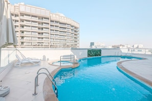 A rooftop swimming pool with a view of a high-rise building. - FIRST CLASS | Studio | Lavish Cozy Haven (Dubai Sports City)