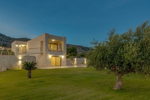A modern two-story house with a stone facade, a balcony, and a well-maintained lawn. - Elios Estate | 22-Guest Villa with Heated Pool (Marathi)