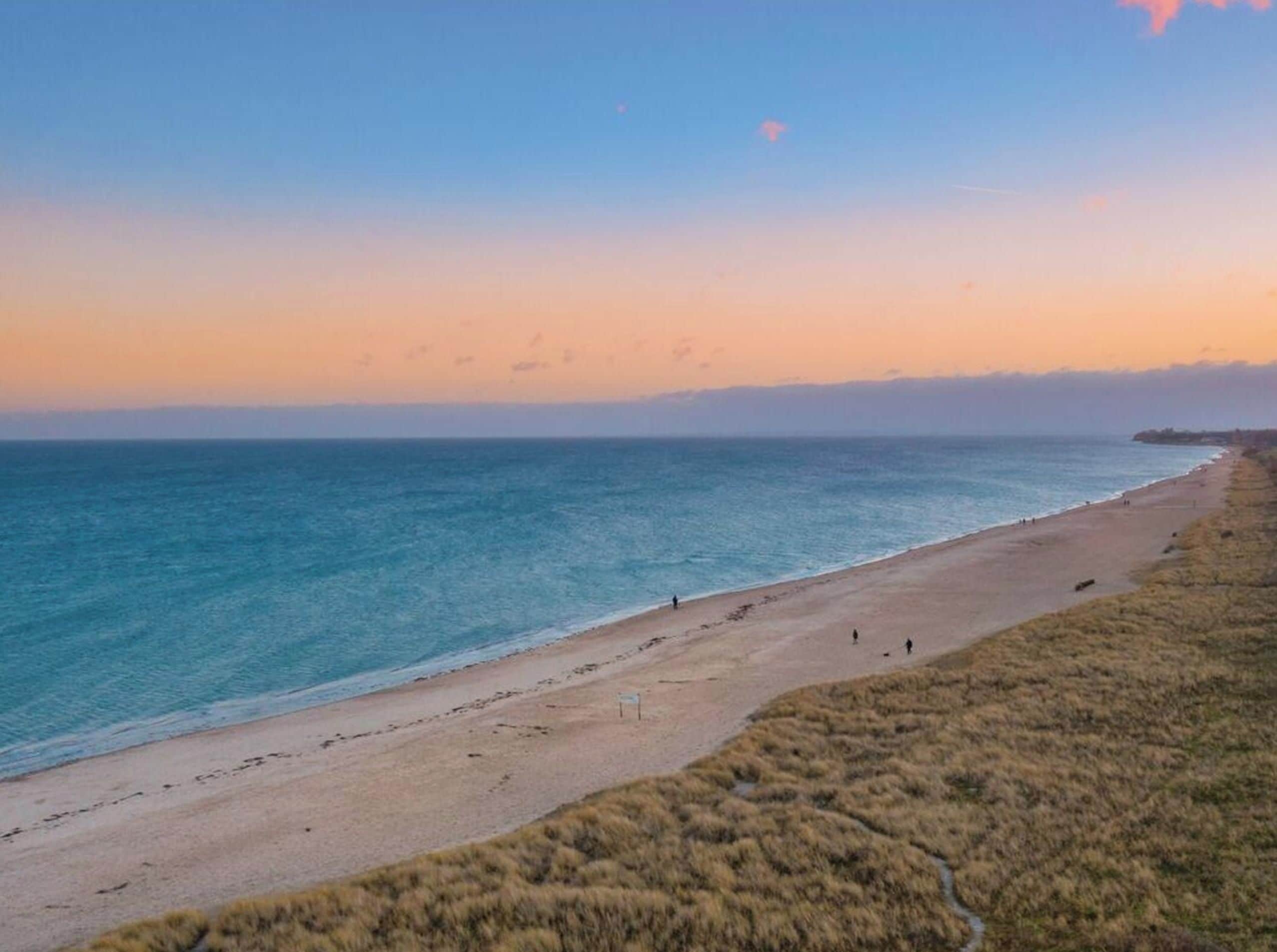 Une plage avec un ciel dégagé et une mer calme.
