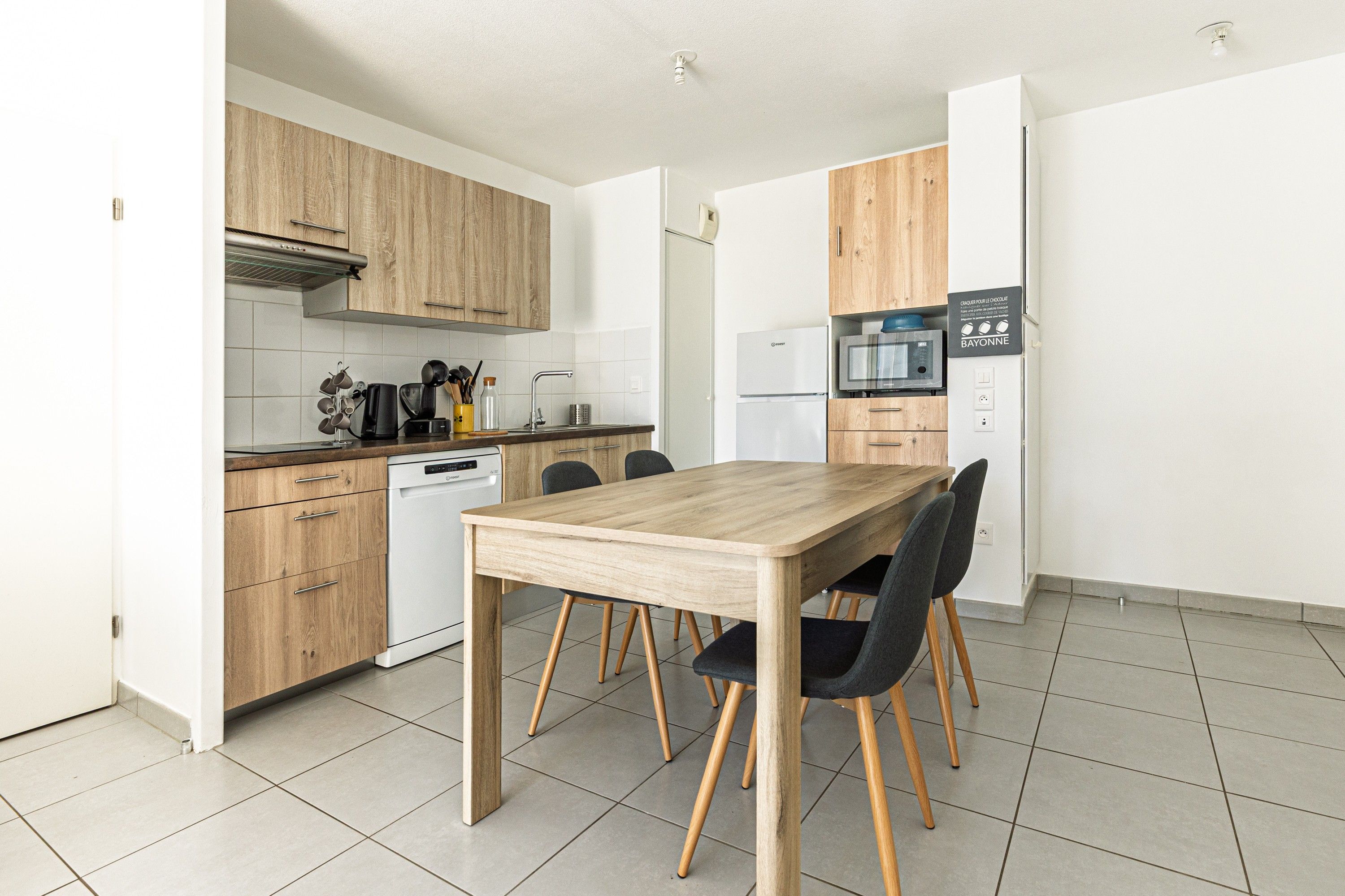 Una cocina moderna con armarios de madera, horno empotrado y una mesa de comedor con sillas.