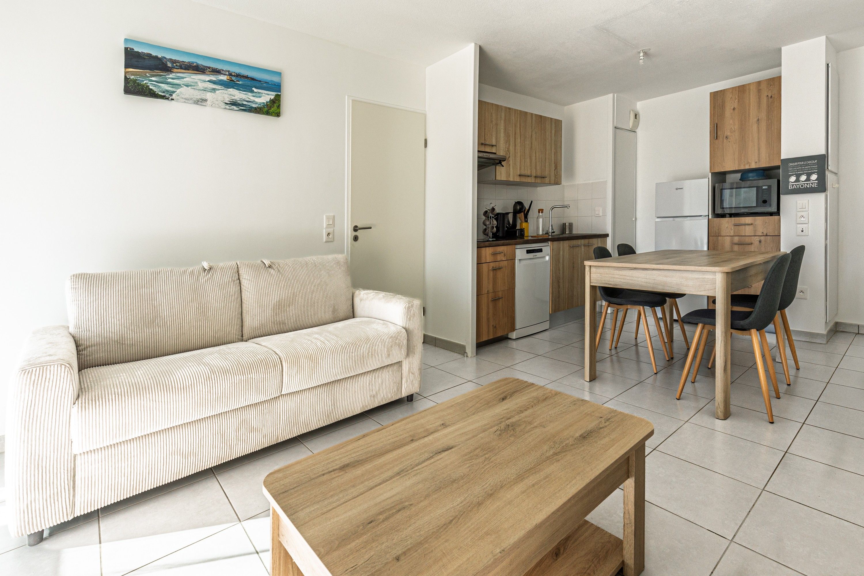 Un espacio habitable moderno con un sofá, una mesa de comedor de madera y una zona de cocina.