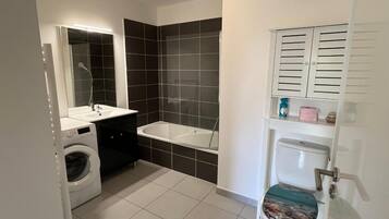 Un baño pequeño con lavadora, bañera y retrete.