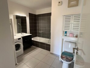 Ein kleines Badezimmer mit Waschmaschine, Badewanne und Toilette.