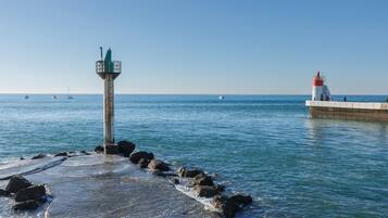 A coastal scene with a lighthouse and a pier extending into the water.