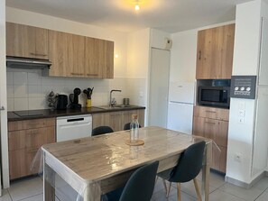 Eine moderne Küche mit Holzausstattung, Geschirrspüler, Mikrowelle und einem Tisch mit Stühlen.
