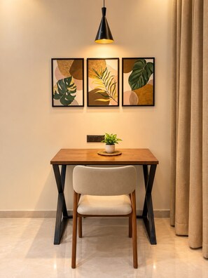 A dining area with a table, chair, pendant light, and framed artwork on the wall.