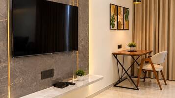 Una sala de estar moderna con un televisor de pantalla plana montado en una pared de mármol, una mesita con una silla y una planta en maceta.