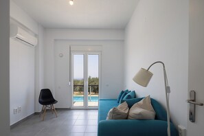 Un salon moderne avec un canapé de couleur turquoise, un fauteuil noir et une lampe sur pied.
