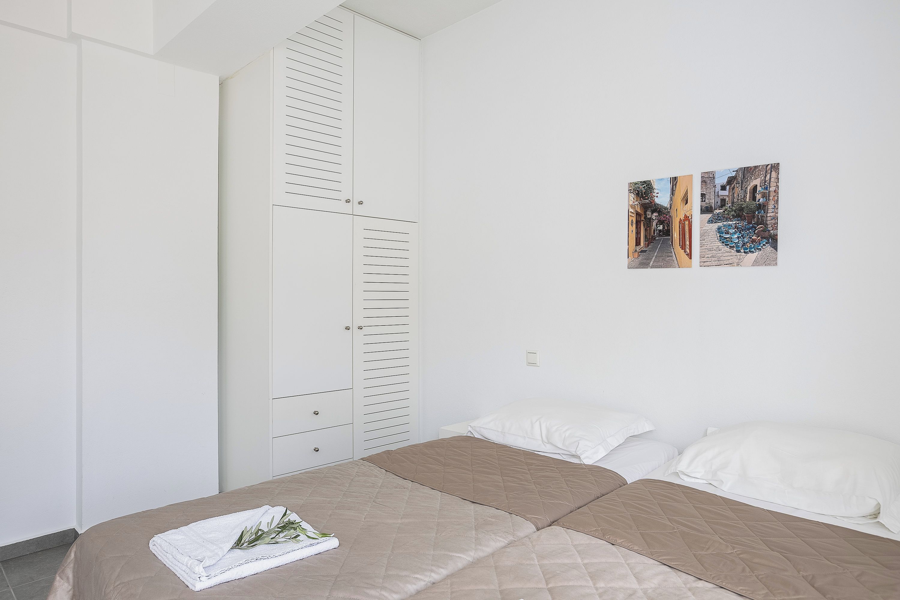 A bedroom with a bed, a wardrobe, and two wall-mounted pictures.