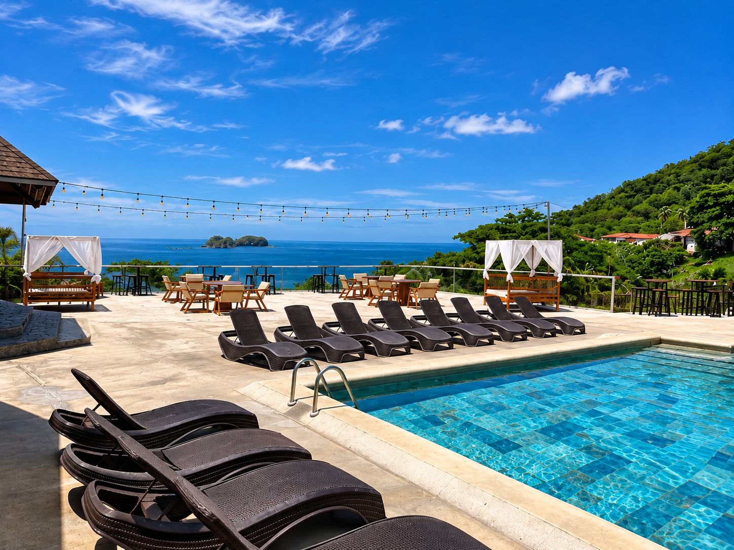 A poolside area with lounge chairs, a small pool, and a view of the ocean.