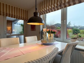 A dining area with a table, chairs, a hanging light fixture, and a view of the outdoors. - Holiday Apartment With 3 Bedrooms (Wyk auf Foehr)