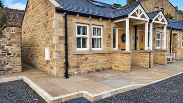 A stone building with a gabled roof, a front door, and a bench outside.