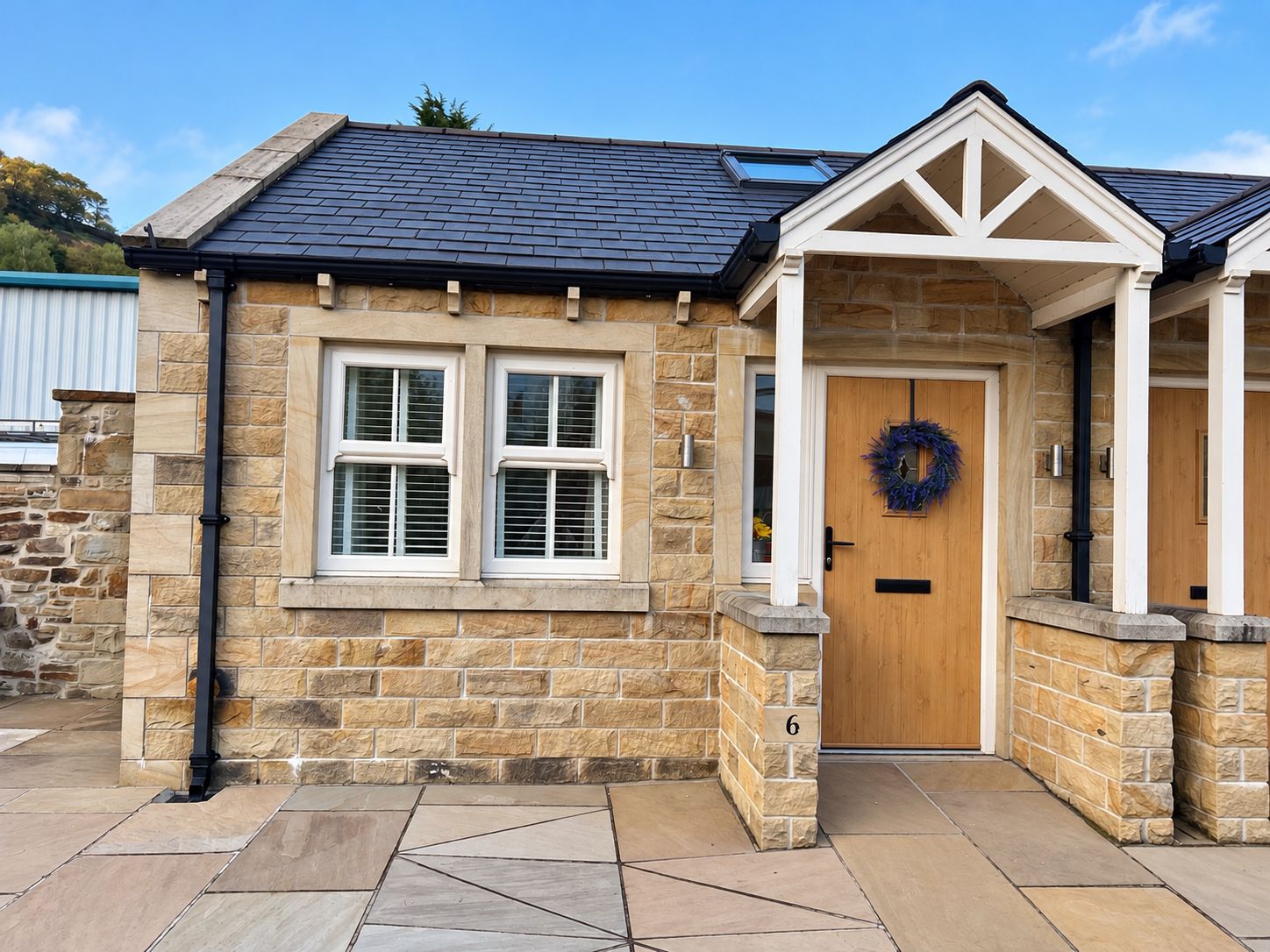 A stone building with a wooden door, a number '6' on the wall, and a wreath on the door.