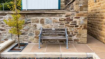 A stone wall with a bench and a tree in front.