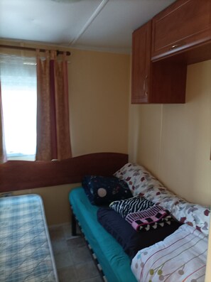 Ein Zimmer mit einem Bett, einem Vorhangfenster und einem Holzschrank.