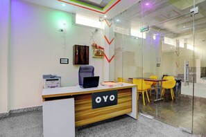 A reception desk with a sign that reads 'OYO,' a laptop, a printer, and a chair.