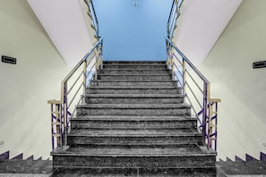Una escalera con barandas de metal y pasamanos, que asciende.
