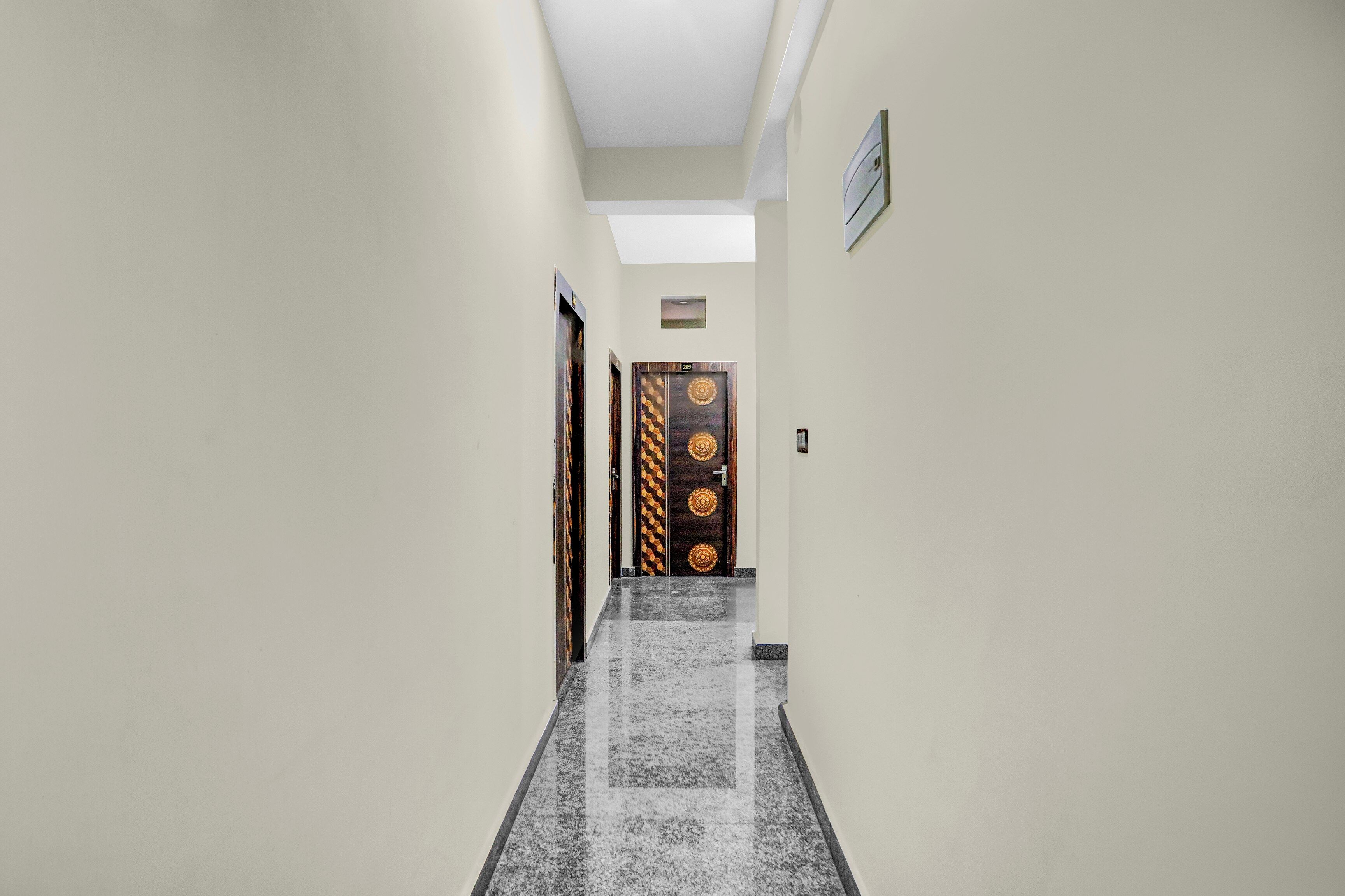 A hallway with a skylight, a door with a geometric pattern, and a small sign above it.