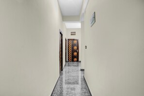 A hallway with a skylight, a door with a geometric pattern, and a small sign above it.