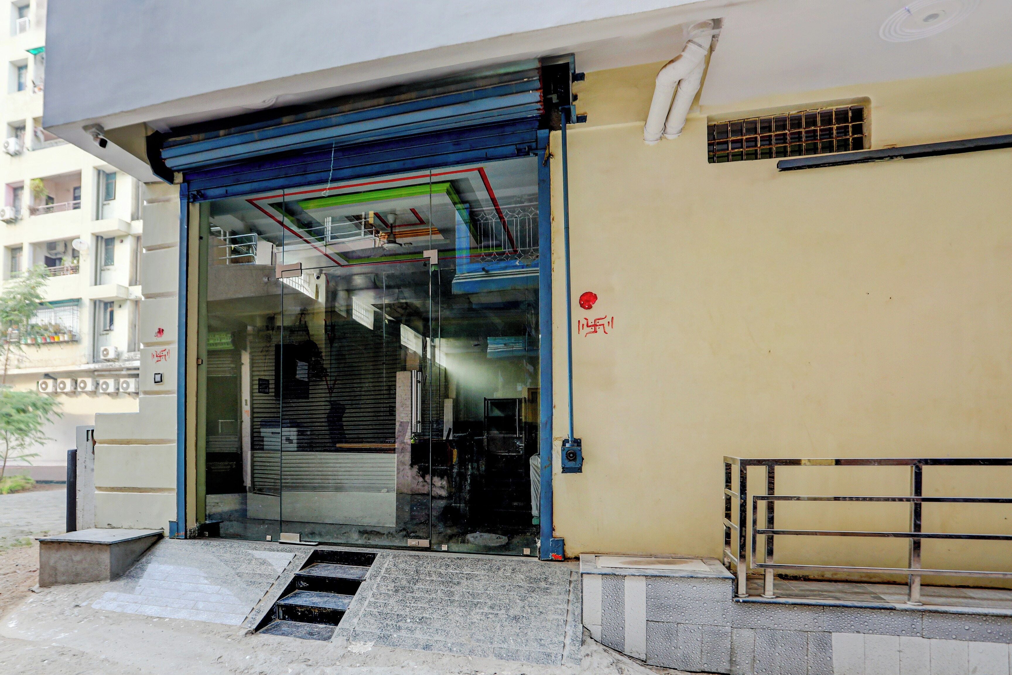 A building entrance with a glass door, a metal gate, and a small set of stairs leading up to the entrance.