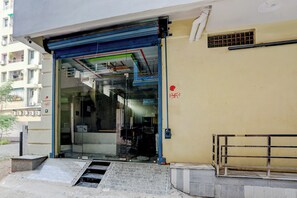 A building entrance with a glass door, a metal gate, and a small set of stairs leading up to the entrance.
