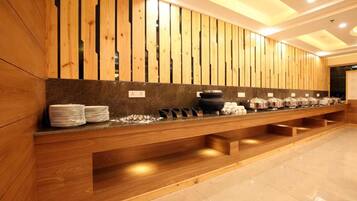 Zona de recepción con mostrador de madera, una barra con platos apilados y una pared con listones verticales de madera.