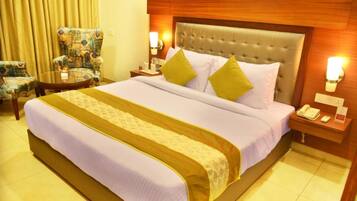 A hotel room with a large bed, two bedside tables, a chair, and a lamp.