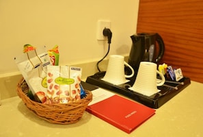 Ein Frühstücksangebot mit einer Korb voller Backwaren, einer Kaffeemaschine und einer roten Speisekarte auf einer Arbeitsplatte.