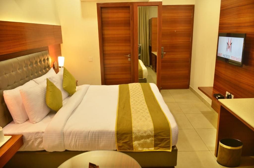 A hotel room with a bed, a TV, a desk, and a mirror.
