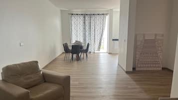 Un salón espacioso con sofá, una mesa de comedor con sillas y una alfombra estampada.