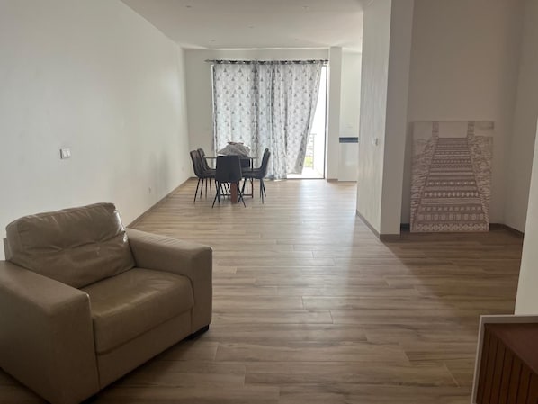 A spacious living area with a sofa, a dining table with chairs, and a patterned rug. - Perfect 3-bedroom apartment in Praia for a relaxing getaway (Praia)