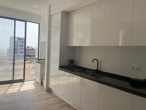 Eine moderne Küche mit schwarzem Arbeitsplatz, weißen Schränken und einem großen Fenster mit Blick ins Freie.